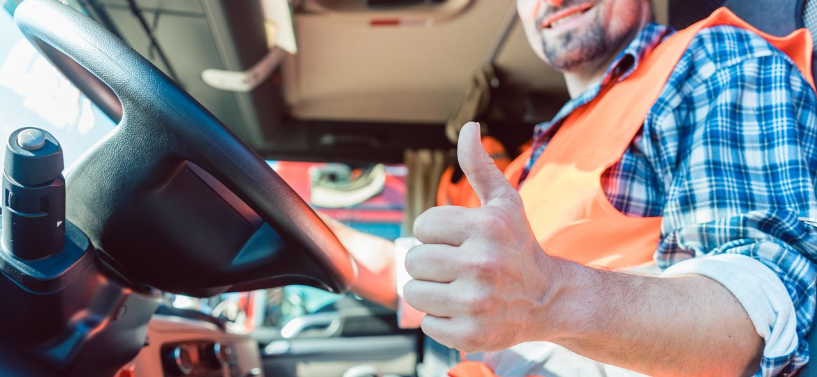 Truck driver sitting in cabin giving thumbs-up